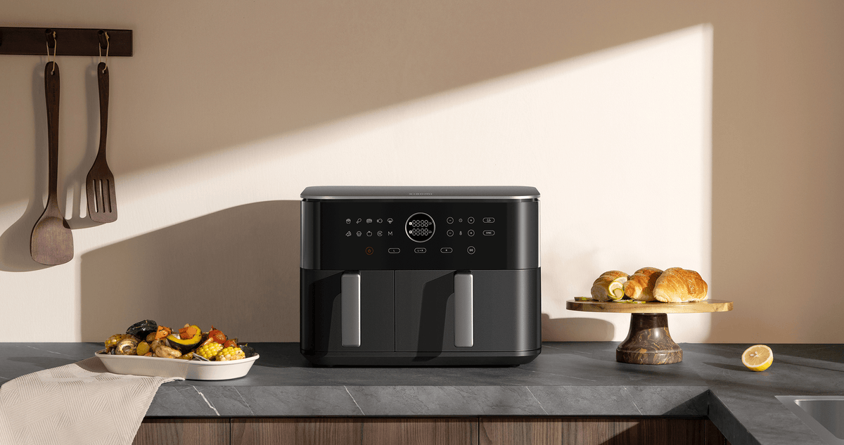 La Xiaomi Dual Zone Air Fryer 10L sobre una encimera de cocina, con una fuente de verduras asadas al lado